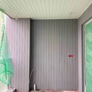 On-site balcony installation showing fir-tone WPC wall siding panels and matching ceiling panels before final finishing.